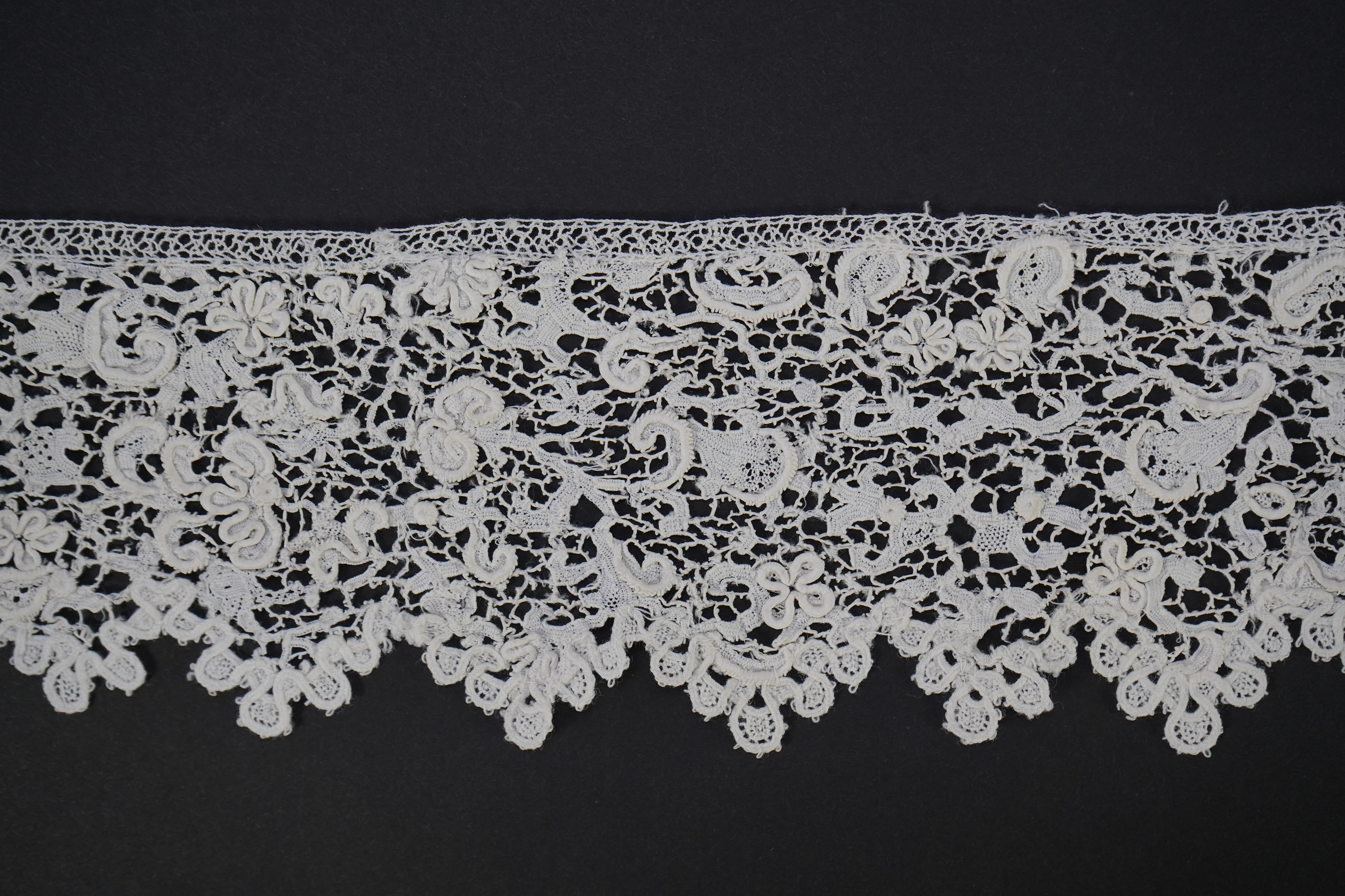 A late 17th century wide flounce of Point de France needle lace, together with a narrower flounce, both with raised elements of the design in the style of Point de Rose, but less so. This lace was very popular with the F